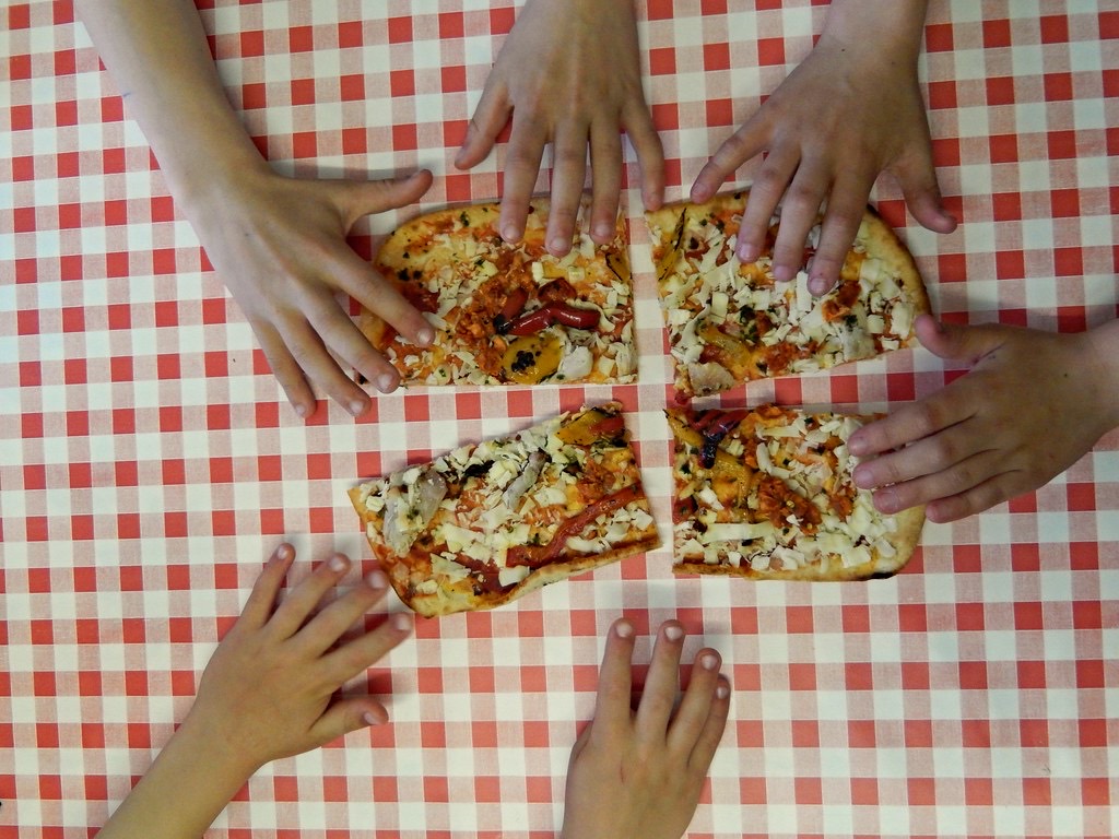 Manos compartiendo comida sobre una mesa al aire libre