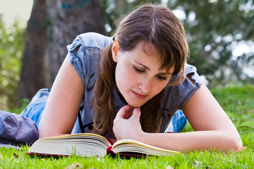 Persona leyendo un libro sobre el pasto