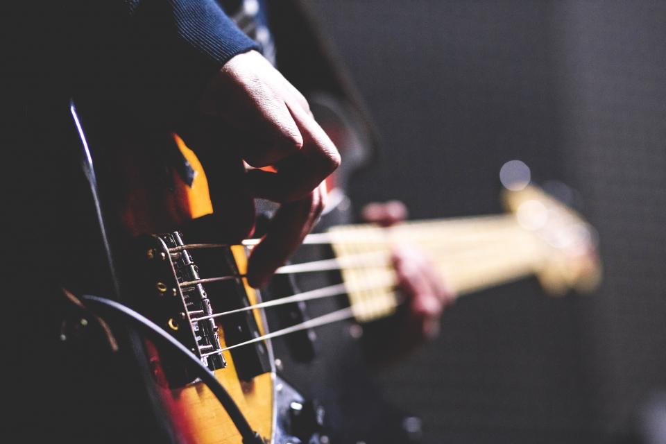 Manos tocando las cuerdas de un bajo eléctrico