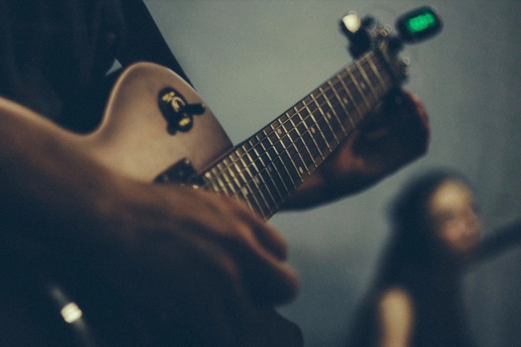 Manos tocando el mástil de una guitarra, foto ilustrativa